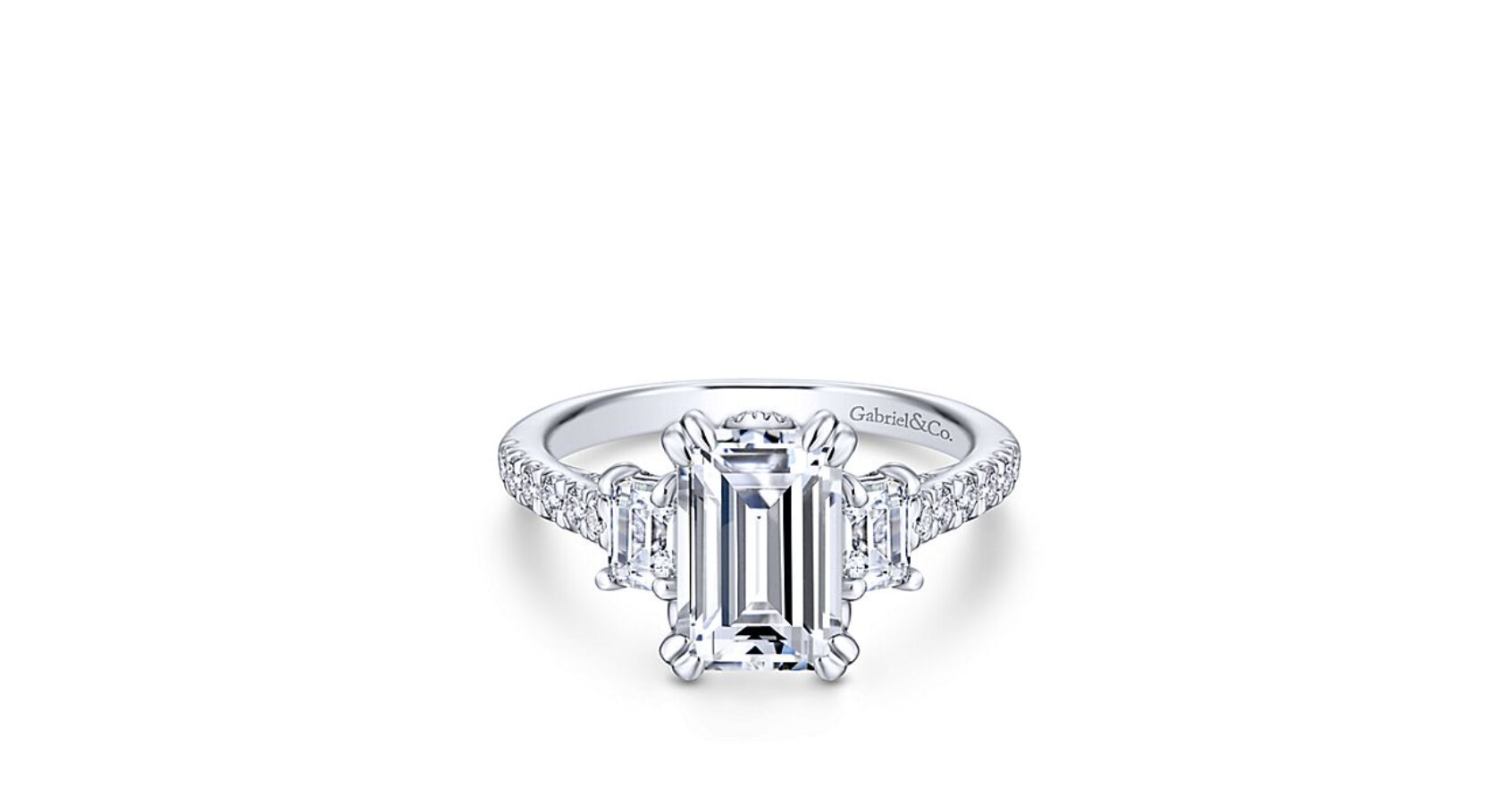 A trio of emerald cut diamonds shine atop this timeless three stone ring. A scalloped pave diamond band increases the glitz and glamour.